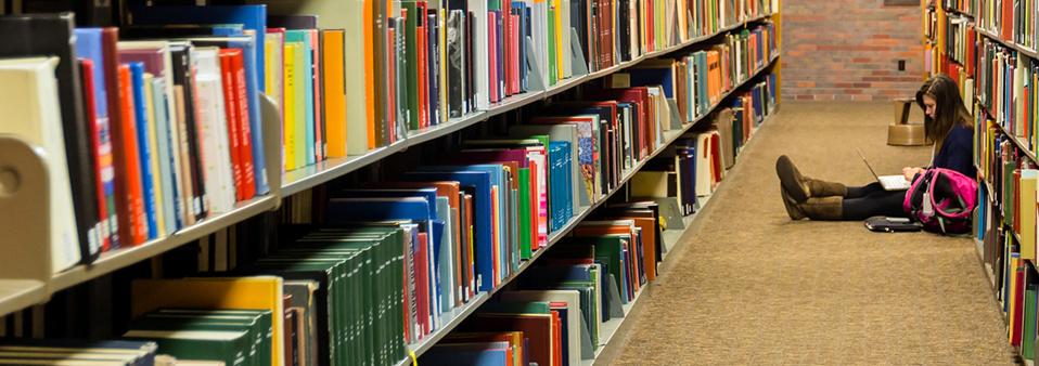 a student sits between the stacks doing research